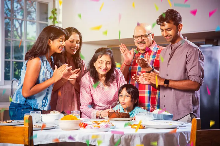 A happy family gathered around a child blowing out birthday candles, celebrating a joyful moment organized by Joyous Events