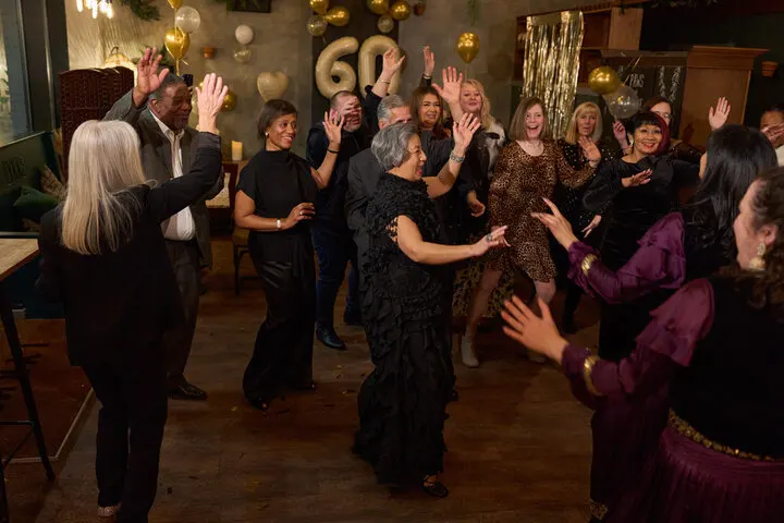 Guests enjoying the dance floor at a 60th birthday party, celebrating with gold balloons and decorations, organized by Joyous Events